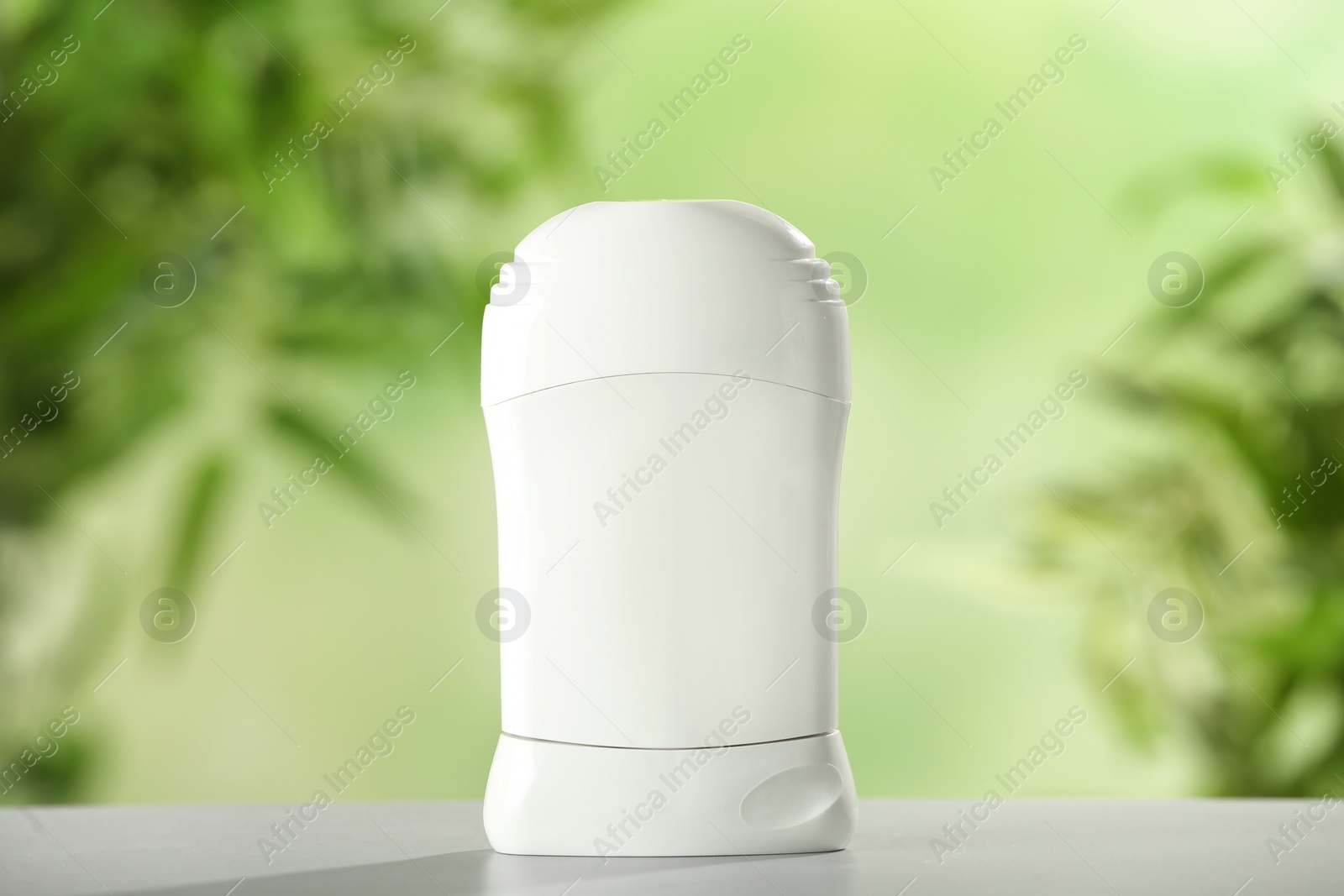 Photo of Deodorant container on white wooden table against blurred background