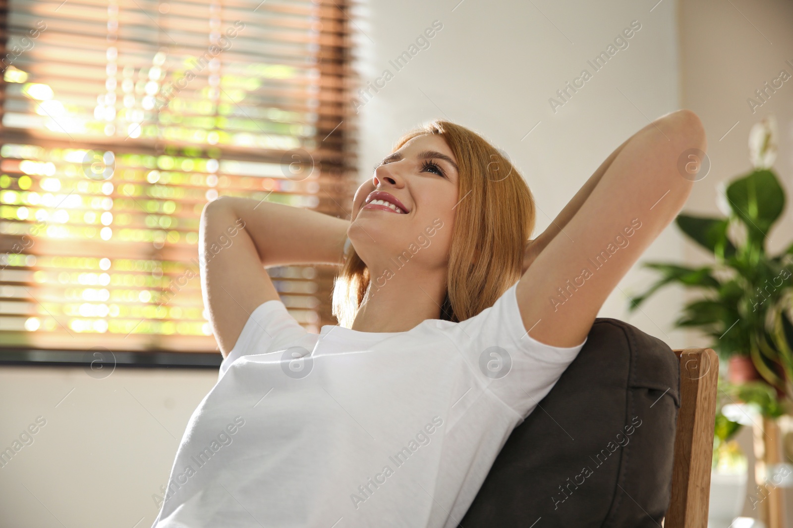 Photo of Young woman relaxing in armchair near window at home