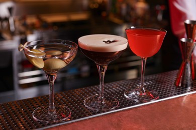 Photo of Glasses of different Martini cocktails on bar counter