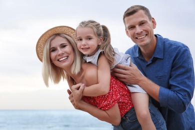 Photo of Happy family spending time together near sea on sunny summer day