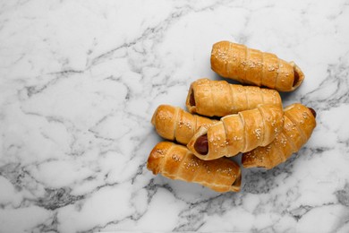 Photo of Delicious sausage rolls on white marble table, flat lay. Space for text