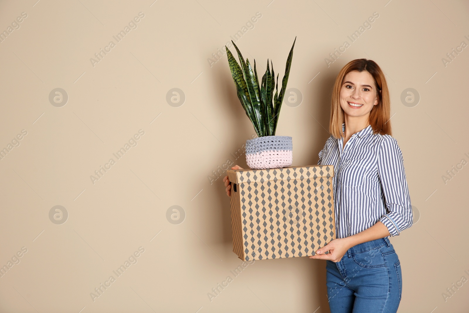 Photo of Woman with moving box and plant on color background. Space for text