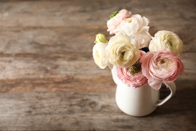 Photo of Vase with beautiful ranunculus flowers on wooden table