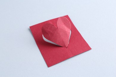 One red paper heart on gray background