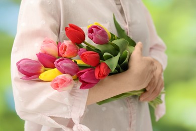 Woman holding beautiful colorful tulip flowers on blurred background, closeup