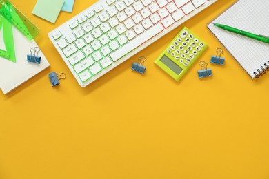 Modern keyboard with RGB lighting and stationery on yellow background, flat lay. Space for text