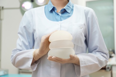 Doctor holding silicone implants for breast augmentation in clinic, closeup. Cosmetic surgery