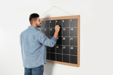 Young man writing with chalk on board calendar