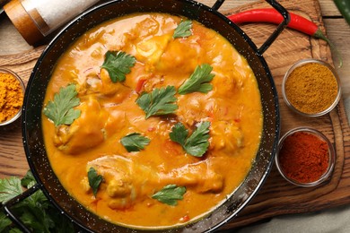 Tasty chicken curry with parsley and ingredients on wooden table, flat lay