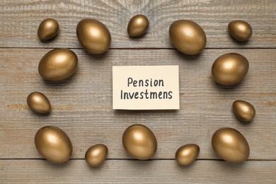 Photo of Golden eggs and card with phrase Pension Investments on wooden table, flat lay