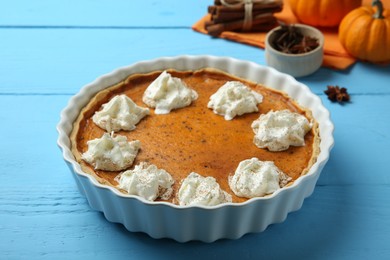 Delicious pumpkin pie with whipped cream on light blue wooden table
