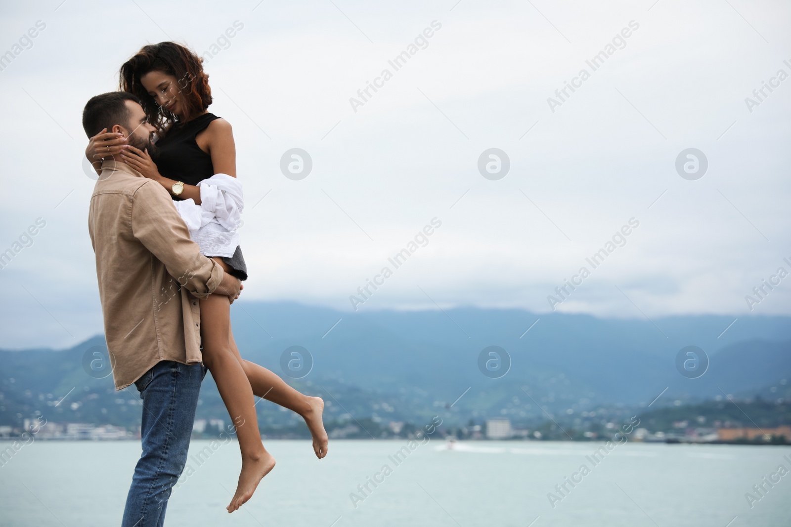 Photo of Beautiful young couple enjoying time together on beach, space for text