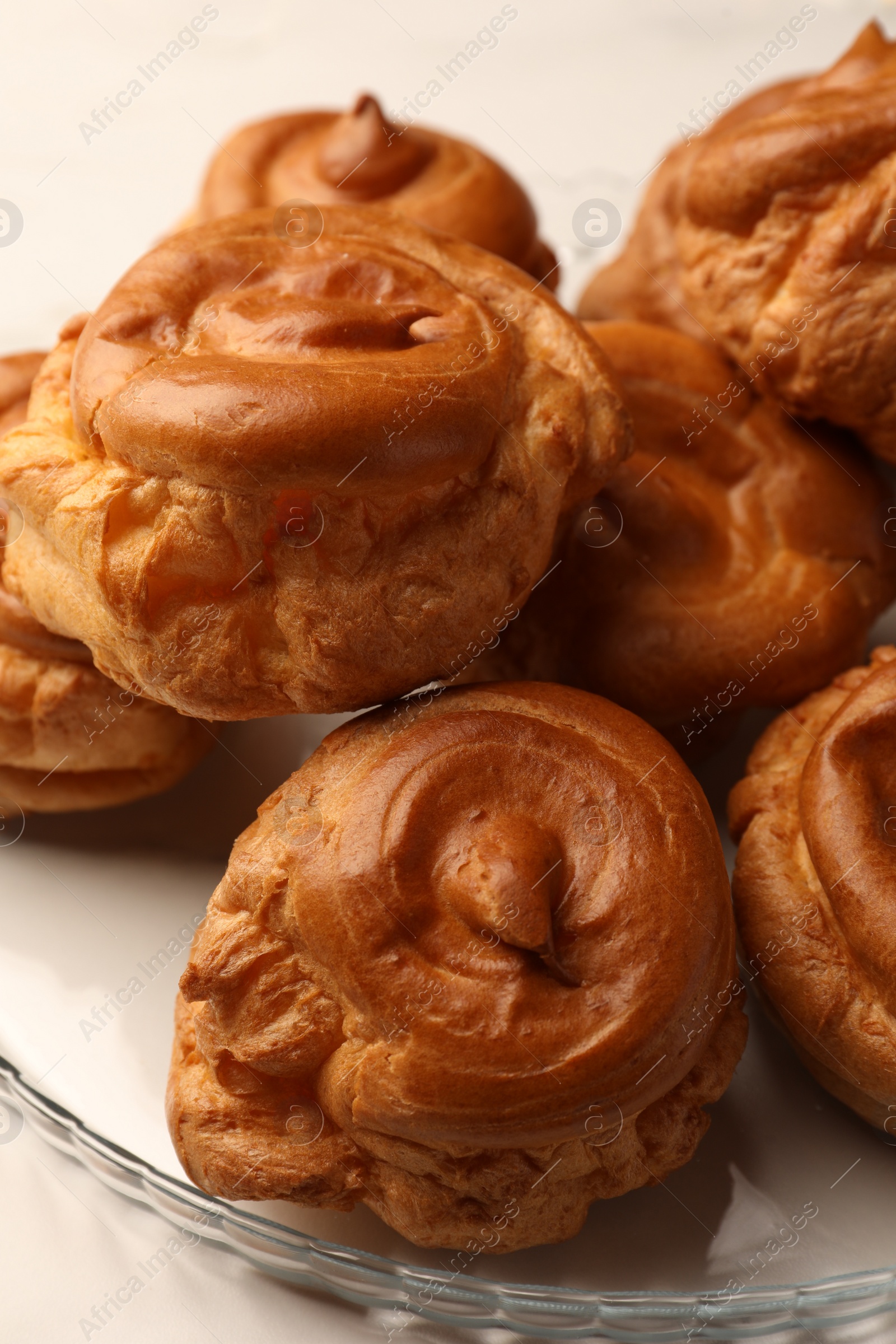 Photo of Delicious profiteroles on white table, closeup view