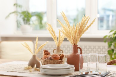 Photo of Clean dishes, dry spikes and fresh pastries on table in stylish dining room