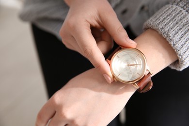 Woman with luxury wristwatch on blurred background, closeup