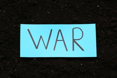 Card with word War on soil, top view