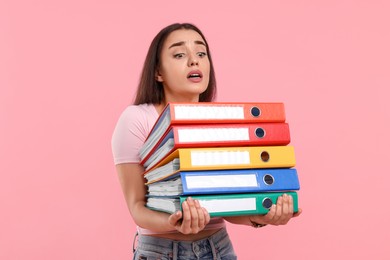 Frustrated woman with folders on pink background