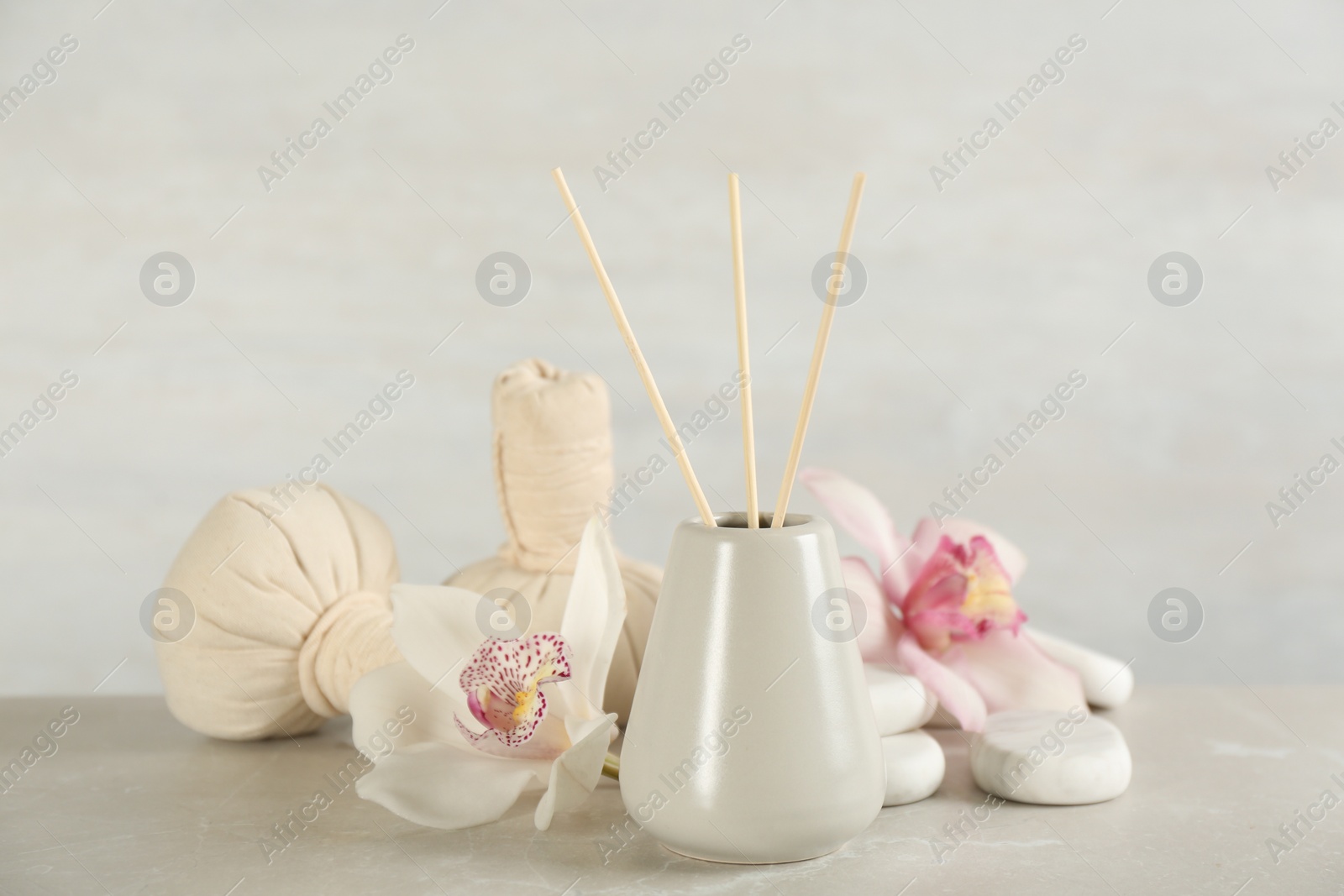 Photo of Beautiful composition with reed air freshener and spa stones on marble table