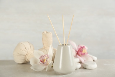 Photo of Beautiful composition with reed air freshener and spa stones on marble table