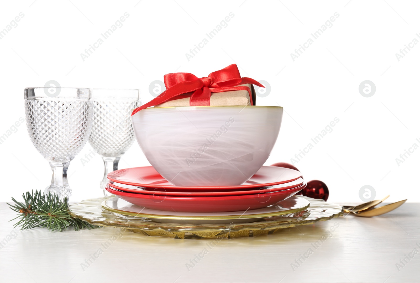 Photo of Festive dishware with gift, glasses and Christmas decorations on white table