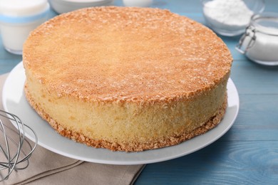Photo of Plate with delicious sponge cake on light blue wooden table, closeup