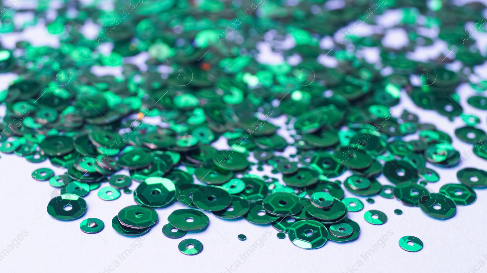 Photo of Many beautiful green sequins on white background. closeup