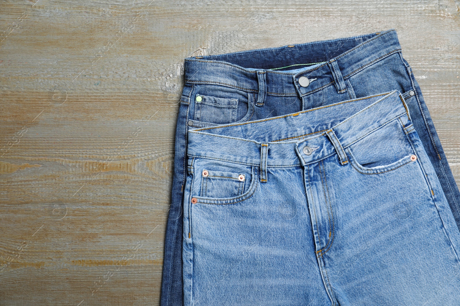 Photo of New stylish jeans on wooden background, flat lay