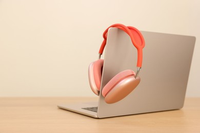 Photo of Modern laptop and headphones on wooden table. Space for text