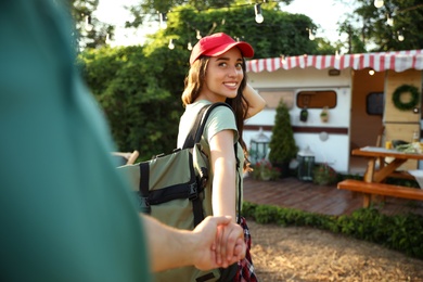 Photo of Young woman with travel backpack holding her boyfriend's hand outdoors, closeup. Summer trip