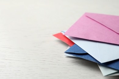 Colorful paper envelopes on white wooden background, closeup. Space for text