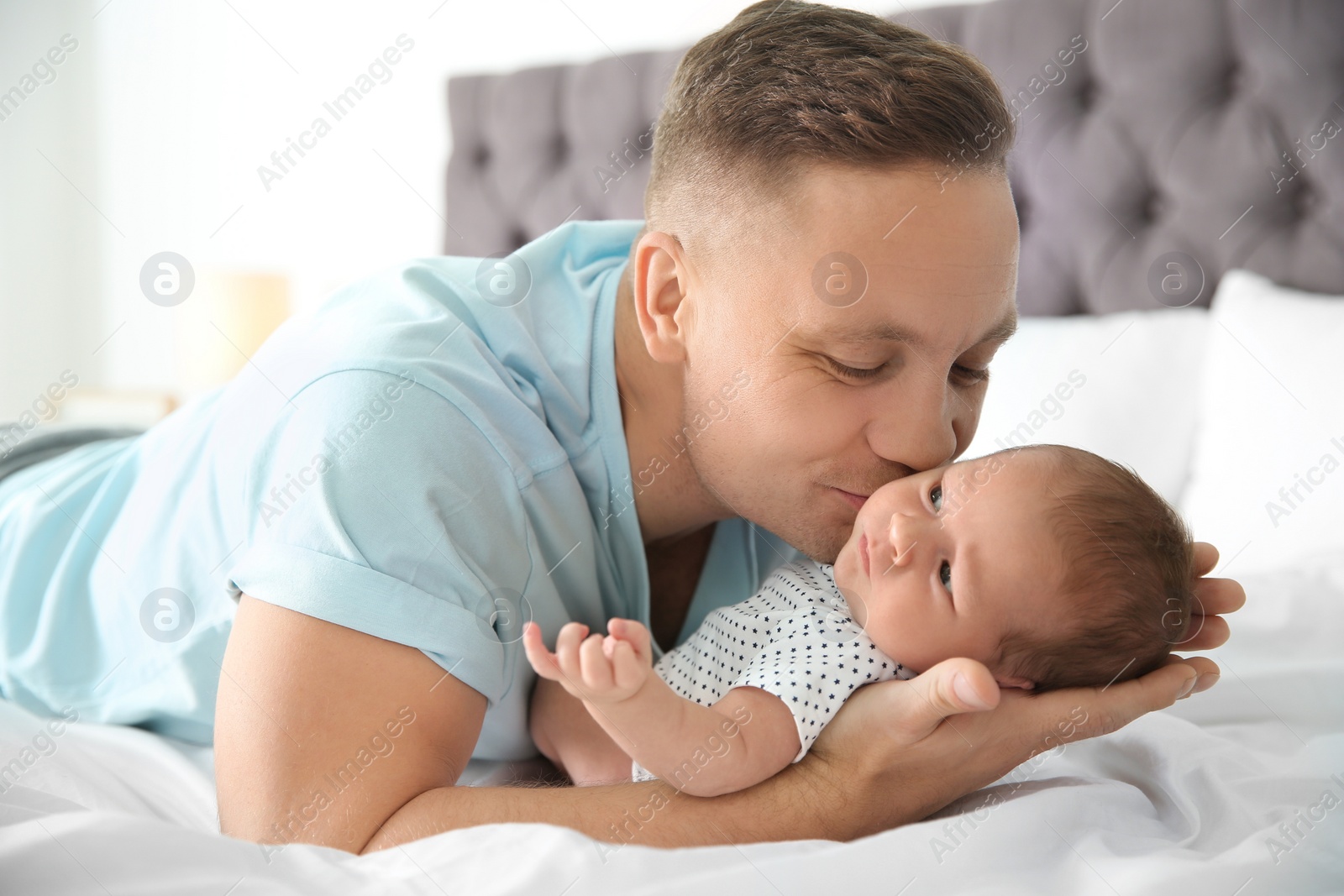 Photo of Man with his newborn baby on bed