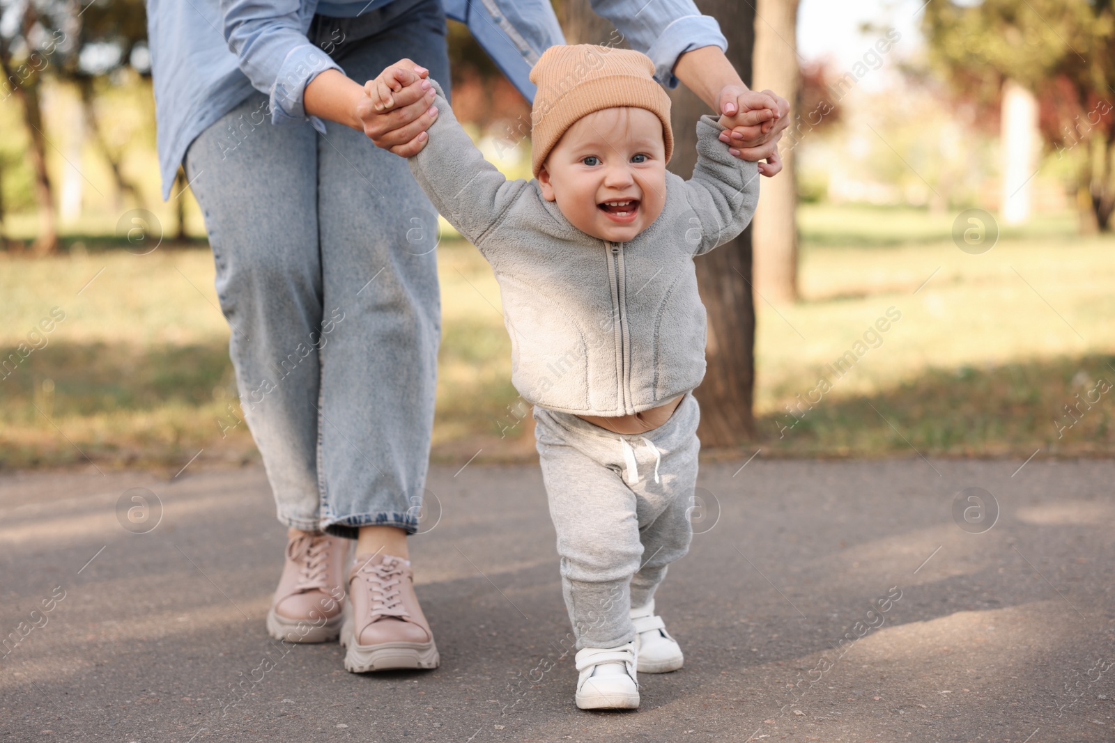 Photo of Mother teaching her baby how to walk outdoors, closeup