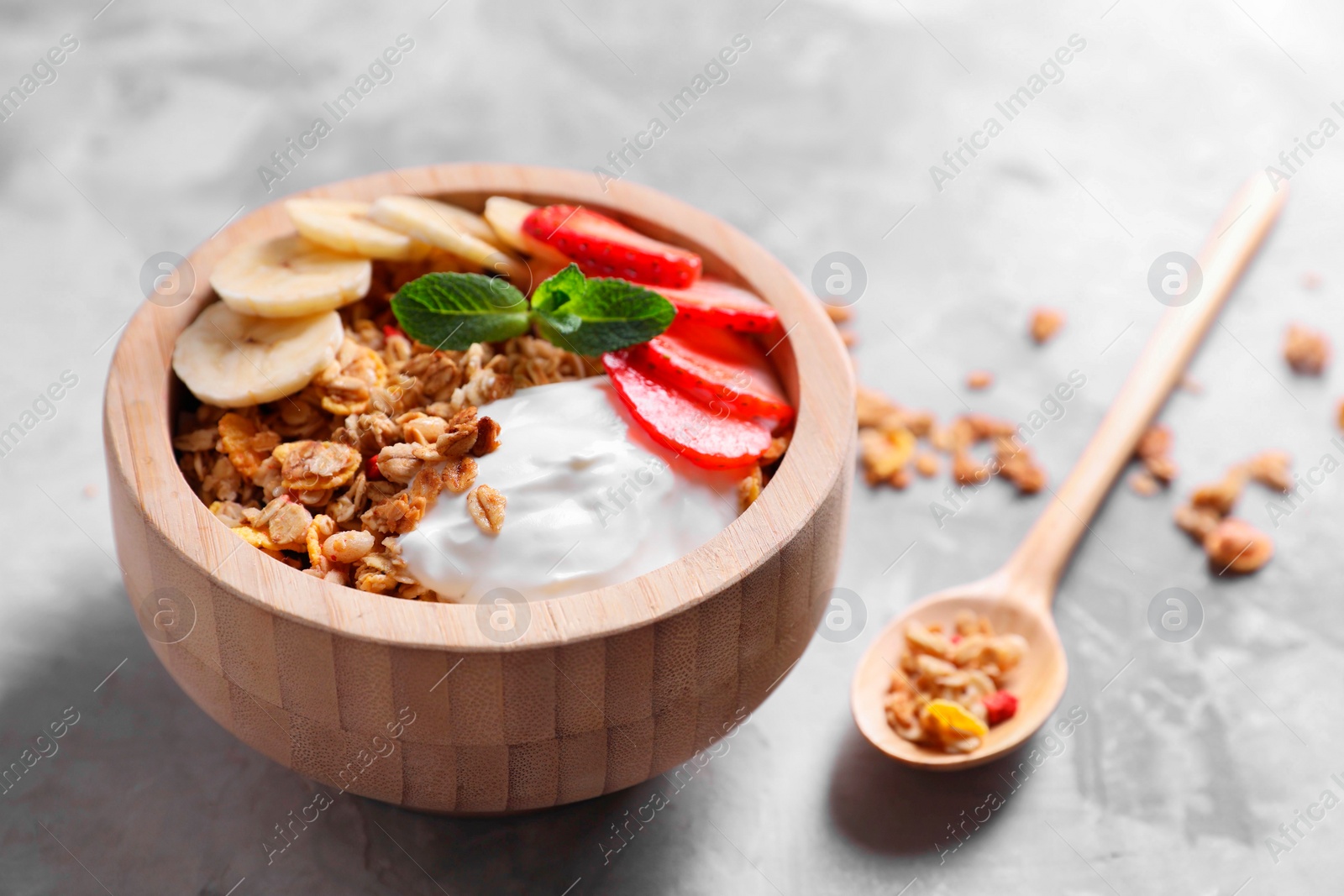 Photo of Tasty granola in bowl served on gray table, closeup