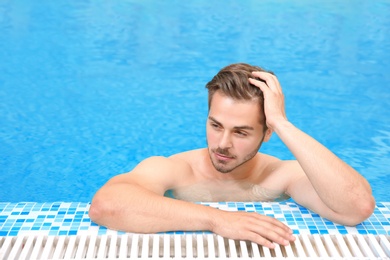 Handsome young man in swimming pool with refreshing water