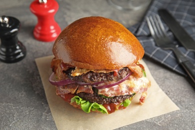 Tasty burger with bacon and lettuce on table