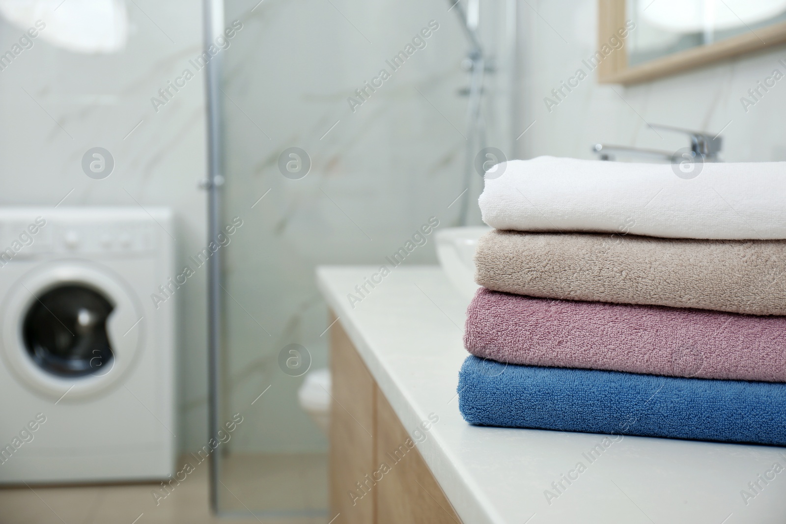 Photo of Stack of fresh towels in bathroom, space for text. Laundry day
