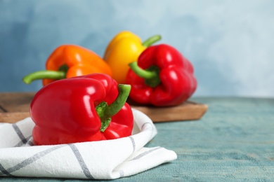 Photo of Fresh ripe bell peppers on wooden table against light blue background, space for text