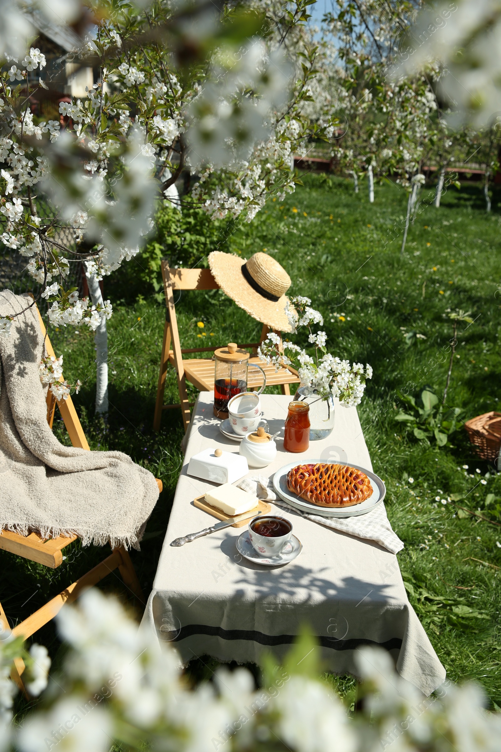 Photo of Beautiful table setting with spring flowers in garden on sunny day