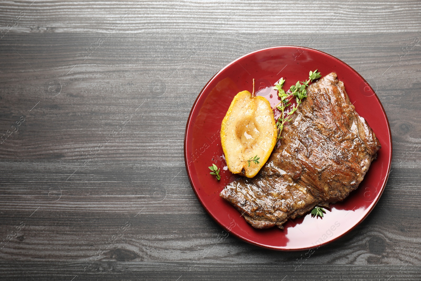 Photo of Delicious roasted beef meat, caramelized pear and thyme on grey wooden table, top view. Space for text