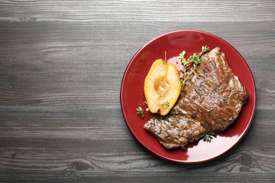 Delicious roasted beef meat, caramelized pear and thyme on grey wooden table, top view. Space for text