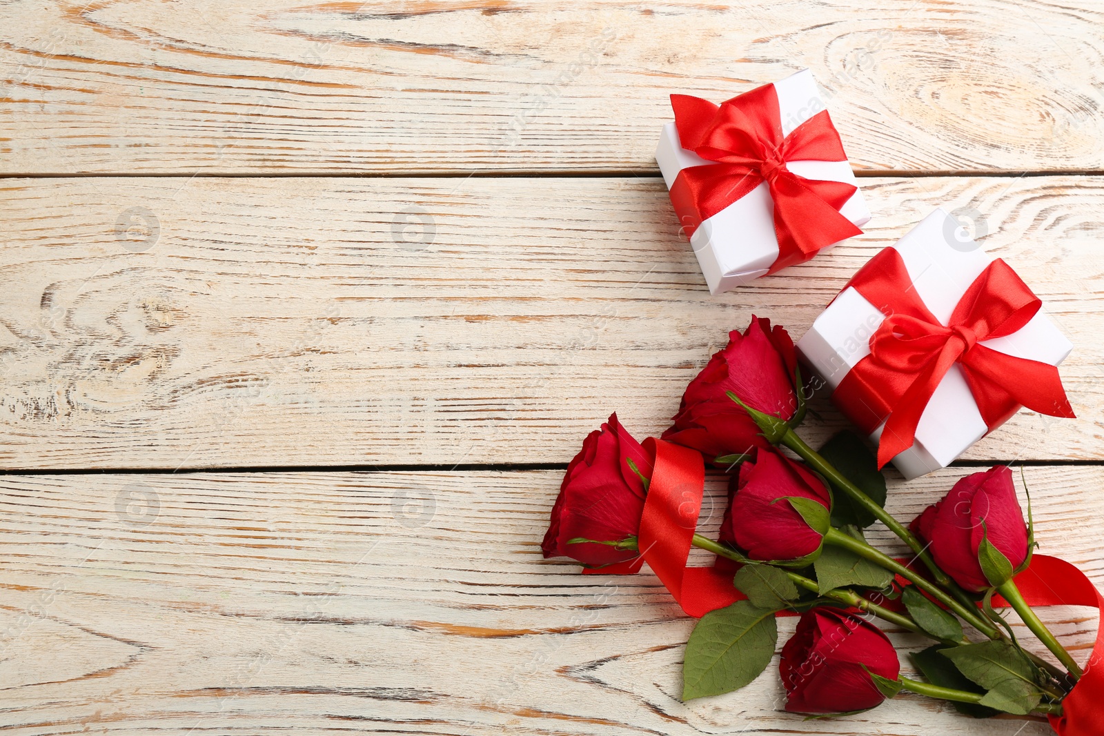 Photo of Beautiful gift boxes and roses on white wooden table, flat lay with space for text. Valentine's Day celebration