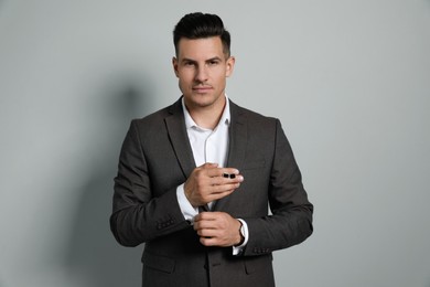 Photo of Handsome stylish man holding cufflinks against grey background