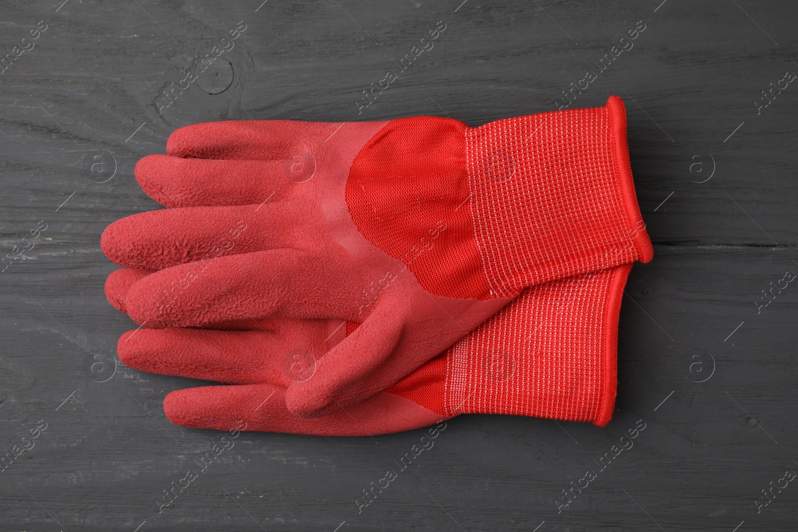 Photo of Pair of red gardening gloves on grey wooden table, top view