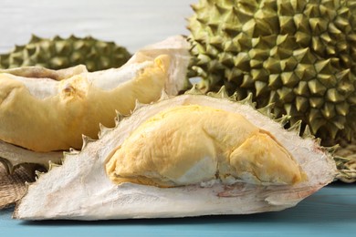 Photo of Fresh ripe durians on light blue wooden table, closeup