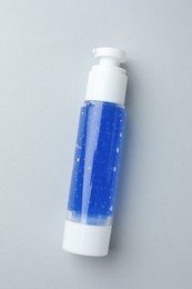 Bottle of cosmetic product on light grey background, top view