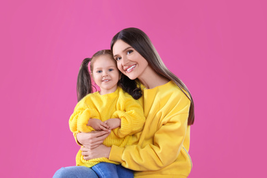 Photo of Young mother and little daughter on pink background