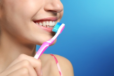 Photo of Young woman with toothbrush on color background, closeup. Space for text