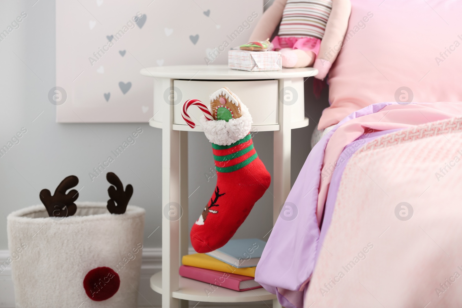 Photo of Stocking with presents hanging on white table in children's room. Saint Nicholas Day tradition