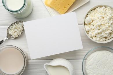 Dairy products and blank card on white wooden table, flat lay. Space for text