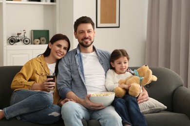 Happy family watching TV on sofa at home